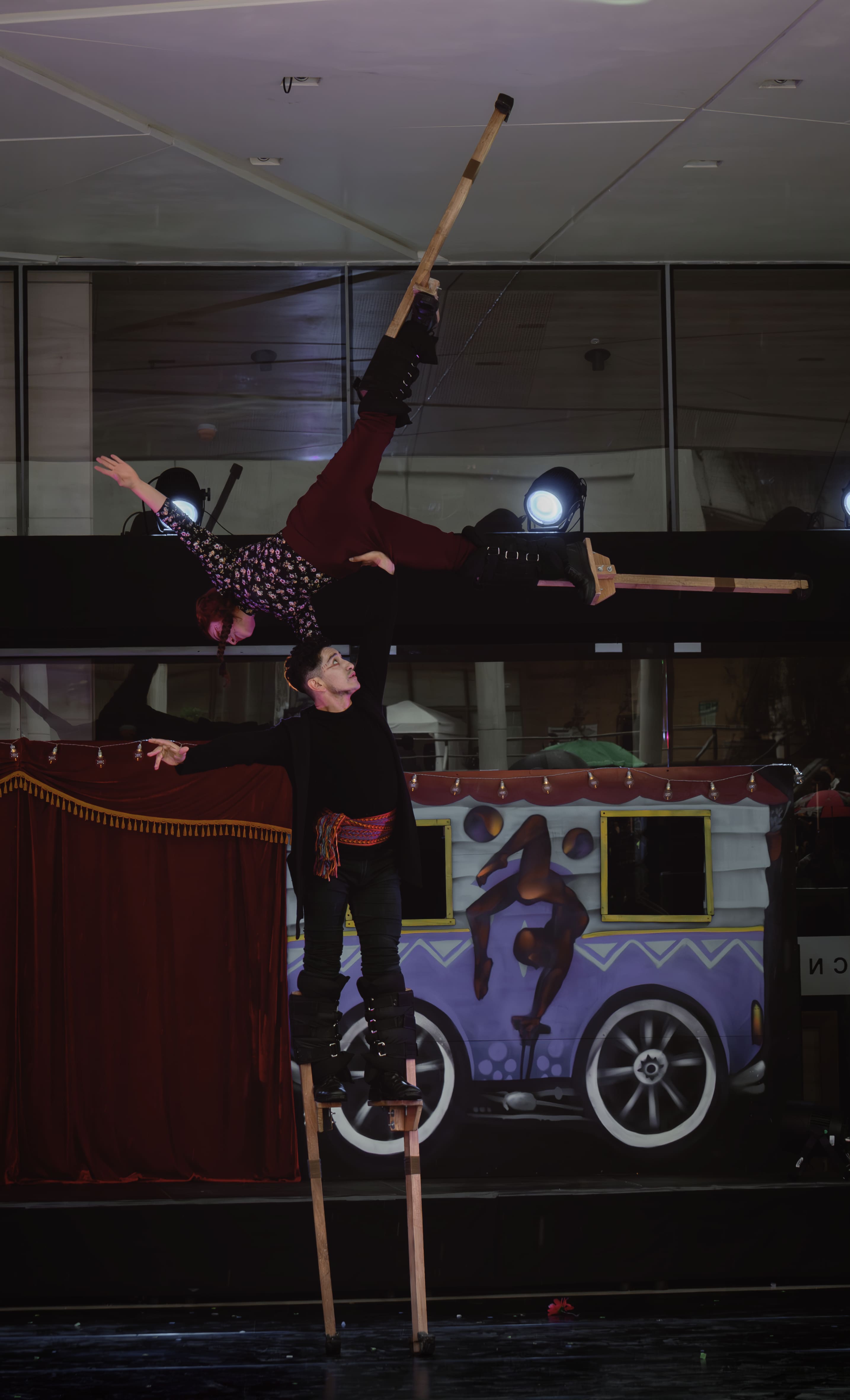 Dos acróbatas en zancos, uno sosteniendo al otro invertido